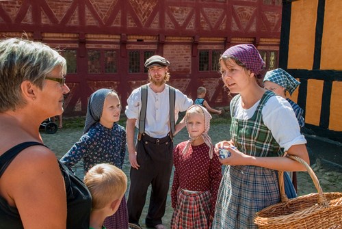 Gæster snakker med en aktør i Den Gamle By.